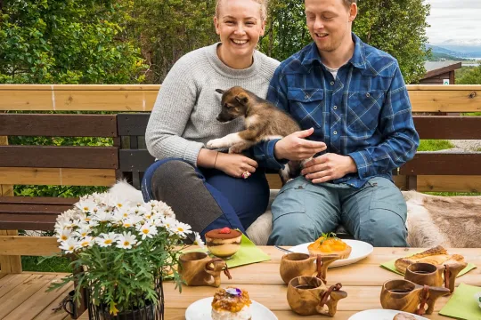 Ett par som koser med en valp, kaffe og kake på bordet