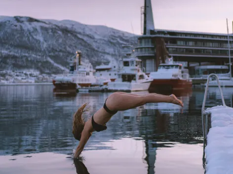 kvine forfriskende dukkert i havet ved Pust sauna i Tromsø
